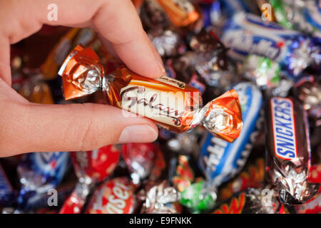 Paphos, Chypre - Décembre 19, 2013 Woman's hand holding Galaxy candy contre fond de bonbons fabriqués par Mars. Banque D'Images