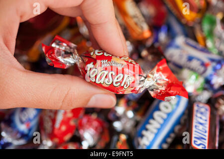 Paphos, Chypre - Décembre 19, 2013 Woman's hand holding Maltesers réflexion candy contre fond de bonbons. Banque D'Images