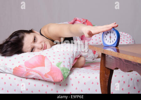 Femme endormie dans son lit, debout à côté d'un réveil sur la table, les endroits sur le 6 heures Banque D'Images