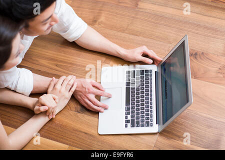 Jeune couple lying on floor using laptop Banque D'Images