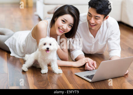 Jeune couple lying on floor using laptop avec un joli chien Banque D'Images