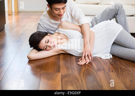 Cheerful young couple lying on wooden floor Banque D'Images