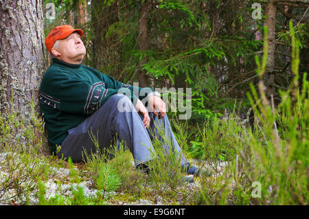 Vieil homme se reposant dans une forêt Banque D'Images