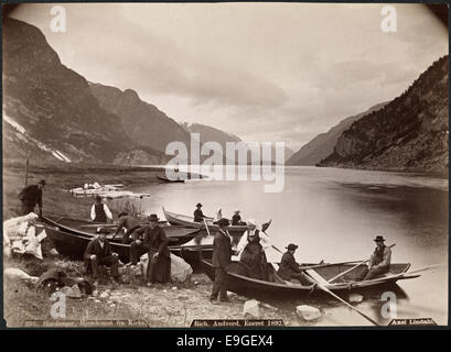 Une photographie du retour de l'église de Hardanger, Norvège, capturant une procession en bateau sur le fjord. L'image montre des personnes en costumes nationaux norvégiens traditionnels (bunader), avec des hommes et des femmes qui rampent dans des bateaux, dans le cadre pittoresque de la région de Hardanger dans le Hordaland. Banque D'Images