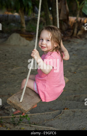 Petit plaisir toddler girl wearing robe rose on swing Banque D'Images