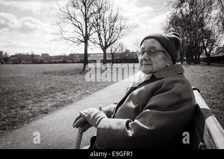 Quatre-vingt-dix ans, femme assise sur banc de parc en automne. L'Angleterre. UK Banque D'Images