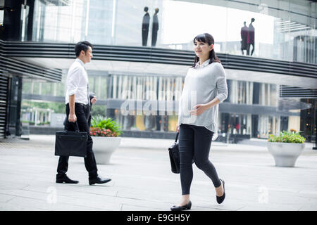 Pregnant businesswoman walking in city center Banque D'Images