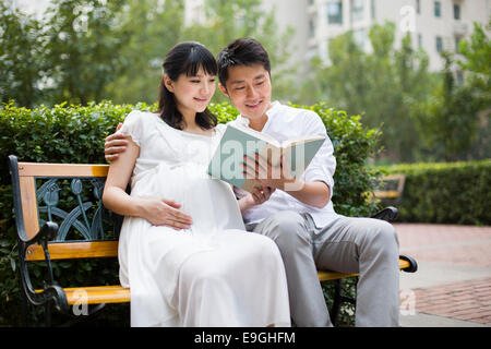 Femme enceinte et son mari la lecture d'un livre Banque D'Images