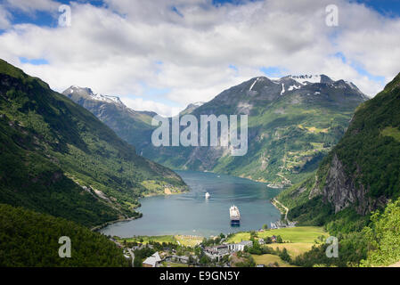 Vue sur un bateau de croisière dans le fjord Geirangerfjord, un site du patrimoine de l'UNESCO, et du village de Geiranger, Norvège. Banque D'Images