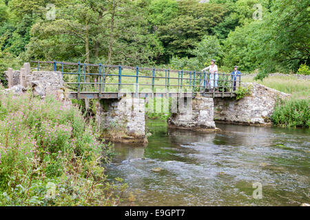 Les personnes qui traversent un pont sur la rivière Wye dans Upperdale dans le Derbyshire Dales, parc national de Peak District, England, UK Banque D'Images