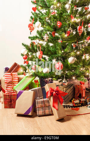 Arbre de Noël magnifiquement décoré avec un petit train et des lots de cadeaux Banque D'Images