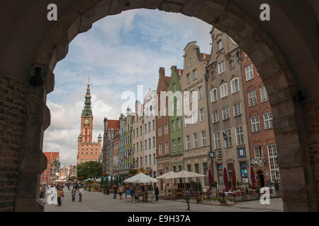 Vue à travers la porte verte ou vers les maisons Zielona Brama sur marché ou la rue Długi Targ et la tour de l'horloge de l'hôtel de ville Banque D'Images