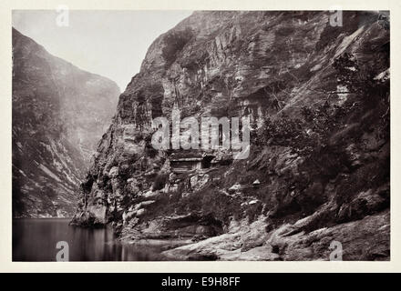 Cette photographie capture le paysage magnifique près de Geiranger, une zone pittoresque à Møre og Romsdal, prise lors de la 'croisière de la Néréide' de 1869. L'image reflète la beauté naturelle des fjords norvégiens, avec des vues spectaculaires sur les montagnes et les eaux environnantes. Banque D'Images