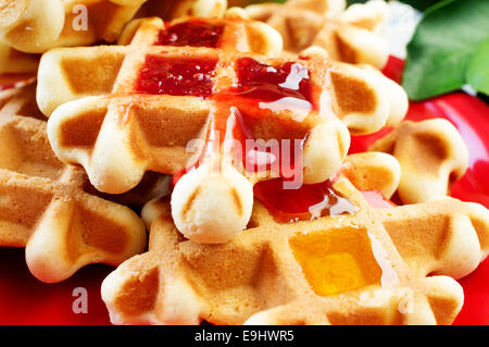 Des gaufres avec du miel et de la confiture de framboises Banque D'Images