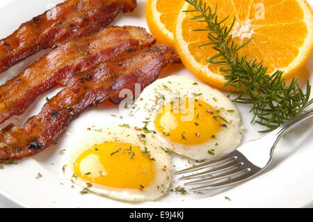 Thick-Sliced Wood-Smoked Apple, du bacon avec deux jaunes d'oeufs avec. Garnir de tranches d'Orange et le romarin. Banque D'Images