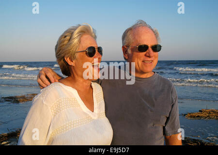 Senior Couple on Beach : Portrait of a senior couple mari et femme sur la plage en face de l'océan au coucher du soleil. Banque D'Images
