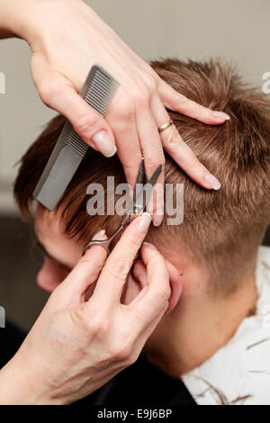 Jeune homme ayant une coupe de cheveux à un salon de coiffure Banque D'Images