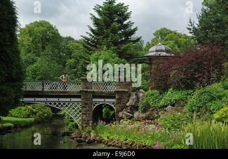 Femme à la recherche sur un pont de fer ornée dans le Pavilion Gardens, Buxton, Derbyshire, Royaume-Uni Banque D'Images