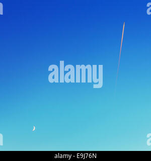 Sentier de l'avion du combustible et de lune sur ciel bleu. Banque D'Images