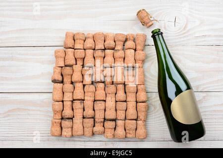 HIgh angle shot d'une bouteille de champagne vide avec étiquette vierge et bouchons. Gros plan sur une table rustique en bois blanc. Format horizontal Banque D'Images