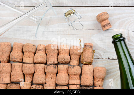 HIgh angle shot d'une bouteille de champagne vides avec bouchons et deux flûtes. Gros plan sur une table rustique en bois blanc. Format horizontal. Banque D'Images