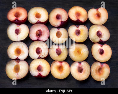 Vingt prunes violettes, coupées en deux avec des pierres Banque D'Images