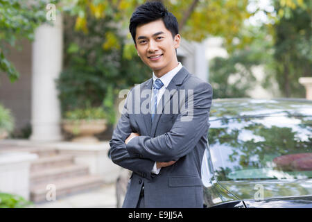 Portrait of young businessman appuyé contre sa voiture Banque D'Images