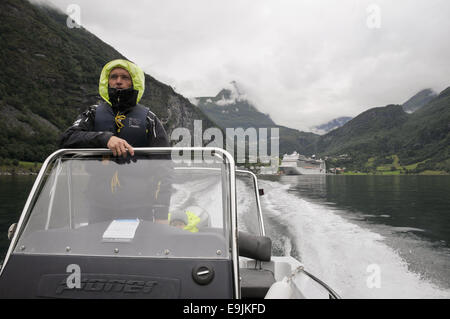 Un bateau-taxi bateau sur le fjord de Geiranger, Norvège, sur la façon d'Skageflå. Un bateau de croisière est amarré au port de Geiranger. Banque D'Images