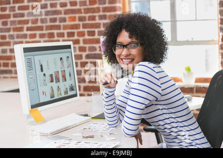 Smiling photo editor at office desk Banque D'Images