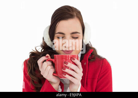 Femme dans les vêtements d'hiver bénéficiant d'une boisson chaude les yeux fermés Banque D'Images