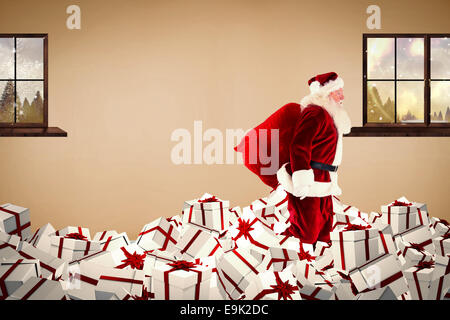 Image composite de santa walking on pile of gifts Banque D'Images