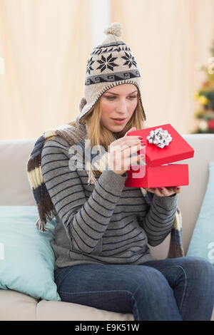 Ouverture d'un cadeau femme blonde assise sur un canapé Banque D'Images