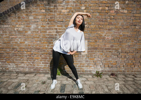 Toute la longueur de l'exercice s'étendant de la scène fit woman against brick wall Banque D'Images