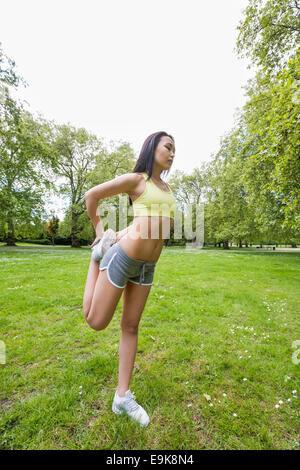 Longueur totale de jeunes fit woman performing exercice s'étendant du park Banque D'Images