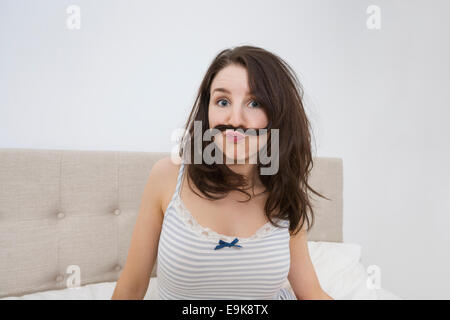 Portrait de femme espiègle avec moustache faite de poils dans le lit Banque D'Images