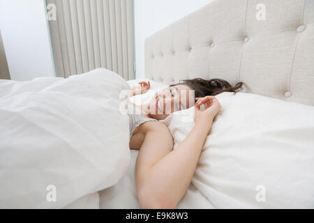 Smiling woman sleeping in bed Banque D'Images