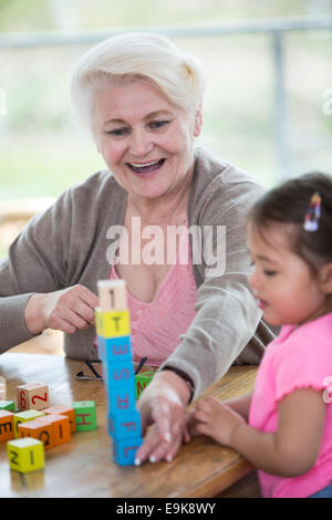 Heureux grand-mère et petite-fille jouant avec alphabet blocks dans chambre Banque D'Images