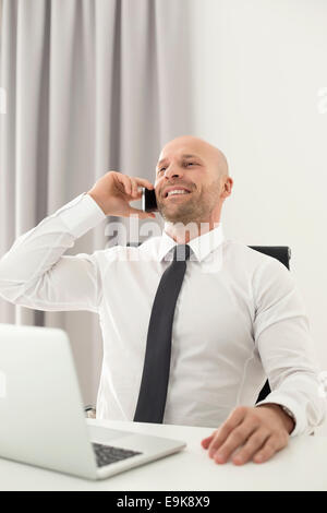 Mid adult businessman on call in home office Banque D'Images