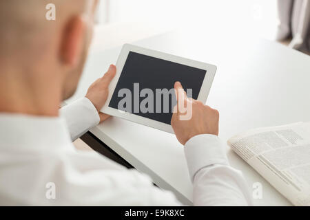 Mid adult businessman using digital computer at table in home office Banque D'Images