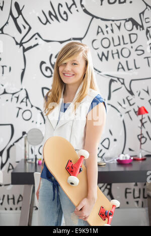 Portrait of teenage girl holding skateboard à la maison Banque D'Images