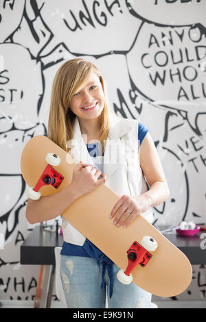 Portrait of teenage girl holding skateboard à la maison Banque D'Images