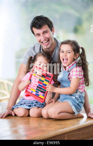 Portrait d'heureux père et filles jouant avec abacus dans chambre Banque D'Images