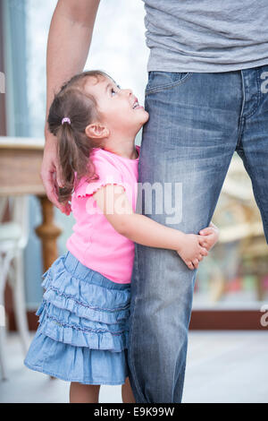 Vue latérale du girl hugging father's leg in house Banque D'Images