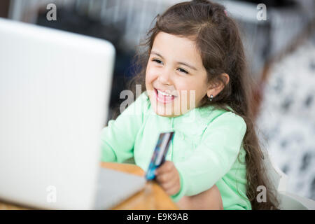 Happy girl using laptop et une carte de crédit pour faire des achats en ligne à la maison Banque D'Images