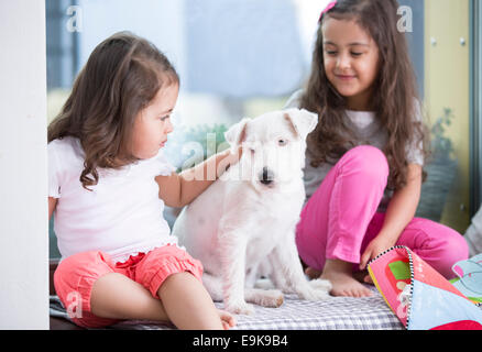 Jolies filles avec puppy sitting on bed Banque D'Images