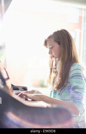 Vue latérale du girl playing piano at home Banque D'Images