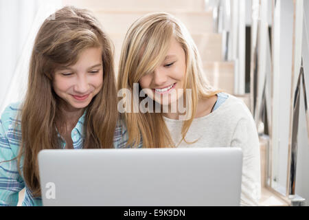 Sœurs using laptop on stairway Banque D'Images