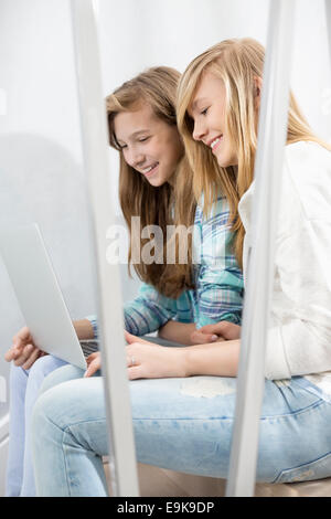 Sœurs using laptop on stairway Banque D'Images