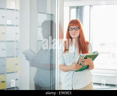 Portrait of businesswoman holding files in creative office Banque D'Images