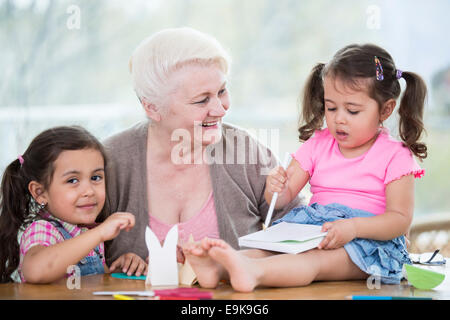 Happy senior femme avec des petites-filles à la maison de l'artisanat Banque D'Images